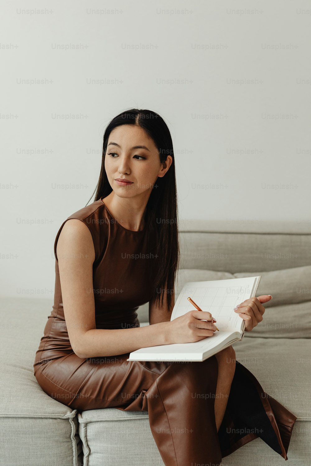 a woman sitting on a couch writing on a book