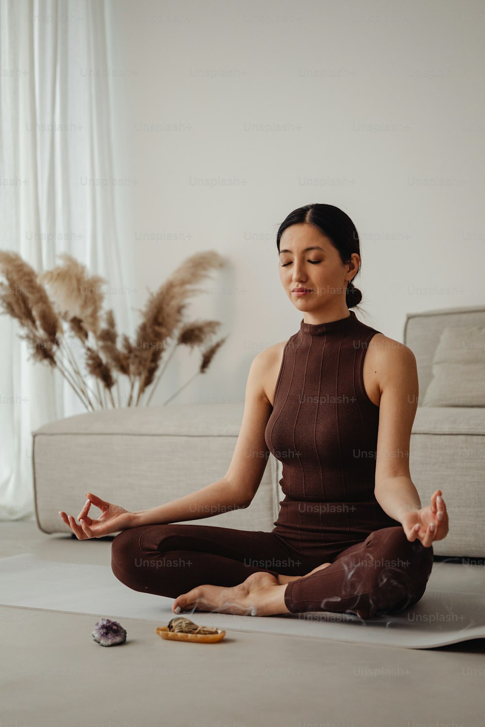 uma mulher sentada em uma posição de yoga com os olhos fechados