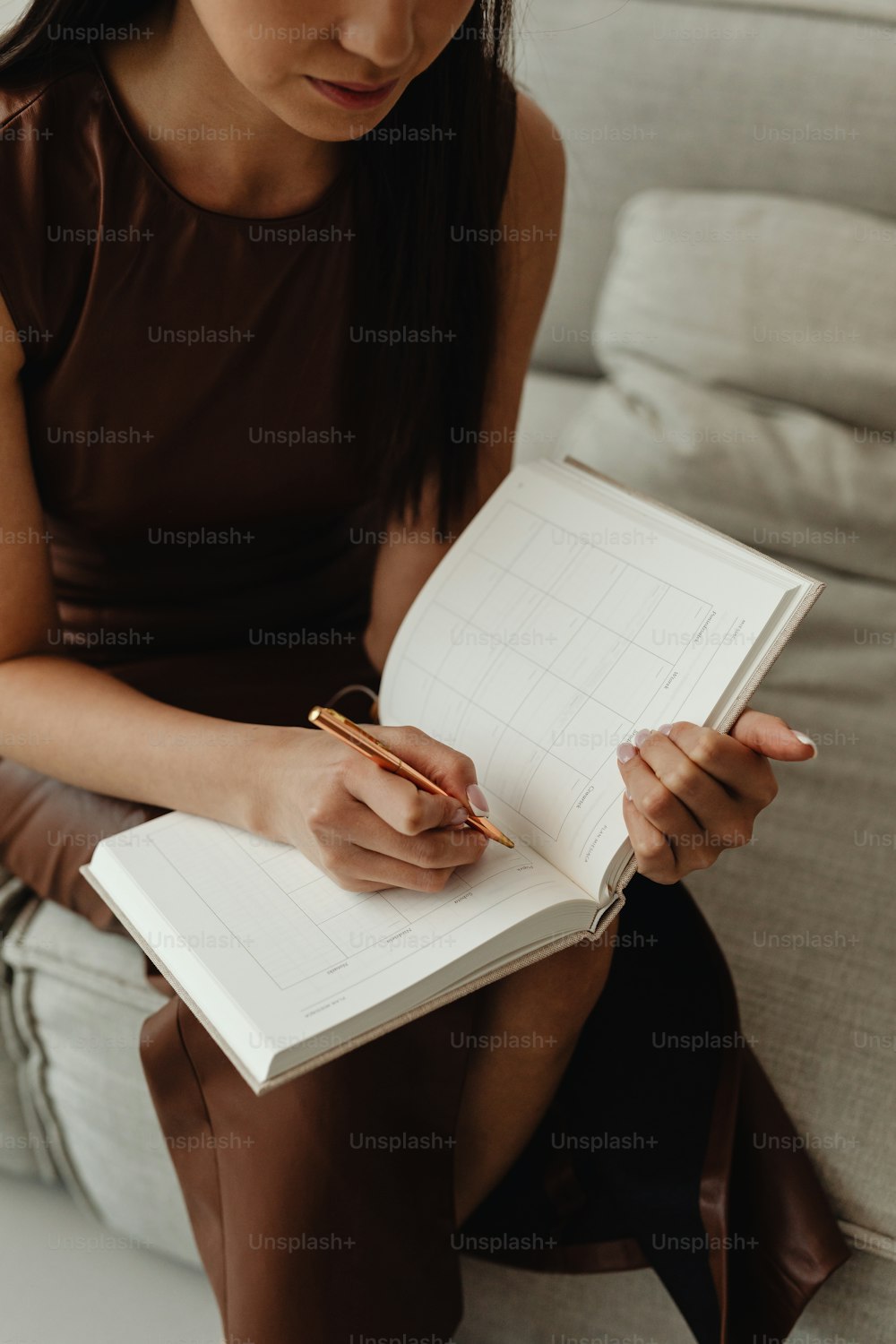 a woman sitting on a couch writing on a book