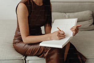 a woman sitting on a couch writing on a notebook