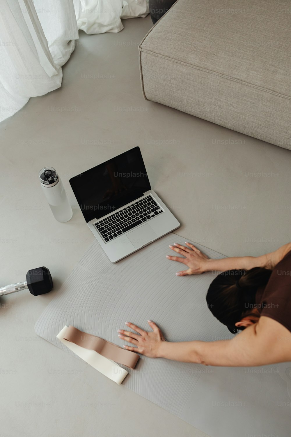 uma mulher deitada em um tapete de yoga usando um laptop