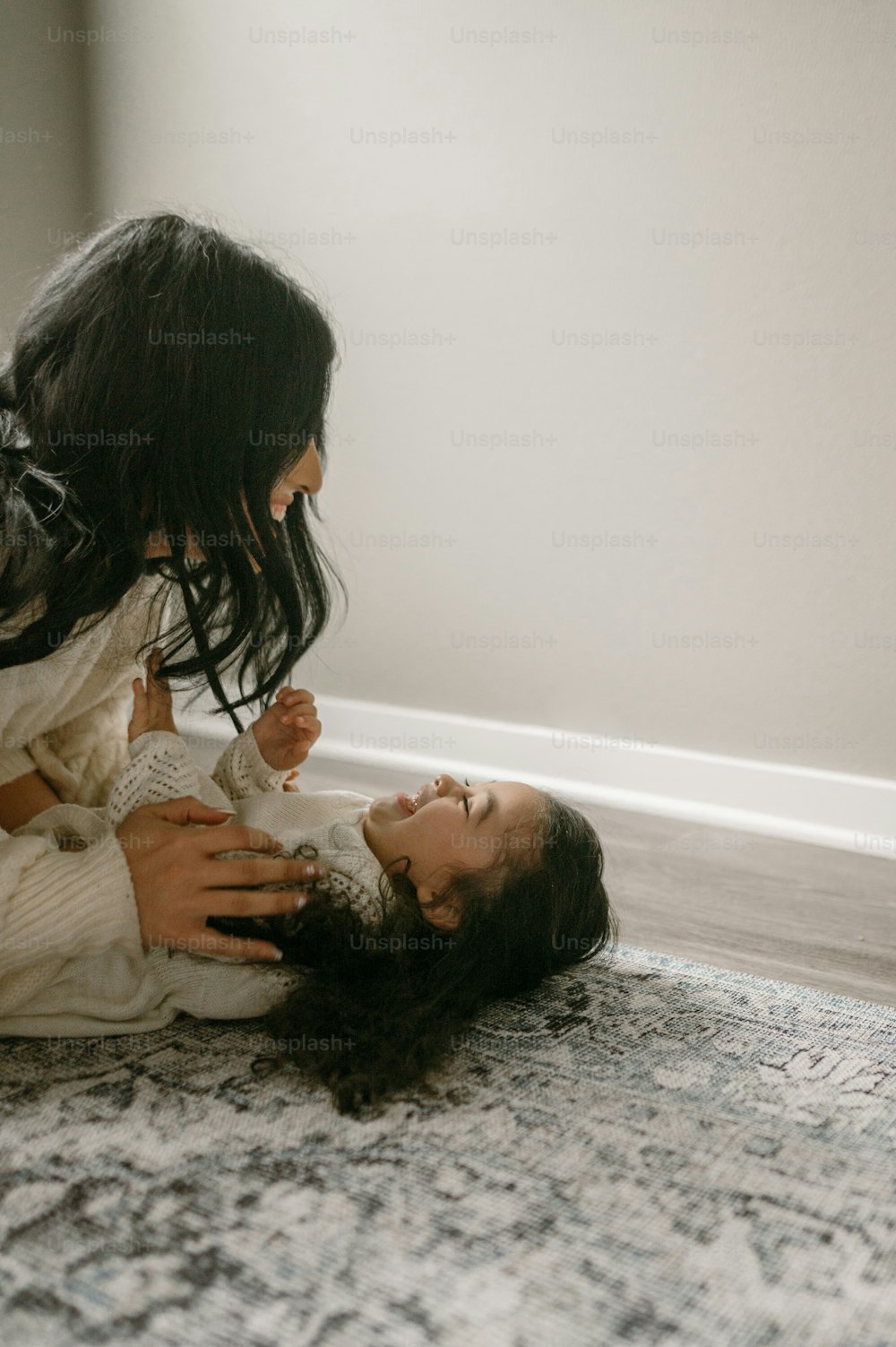 a woman laying on top of a rug next to a child