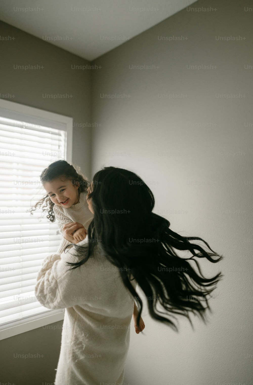 a woman holding a little girl near a window