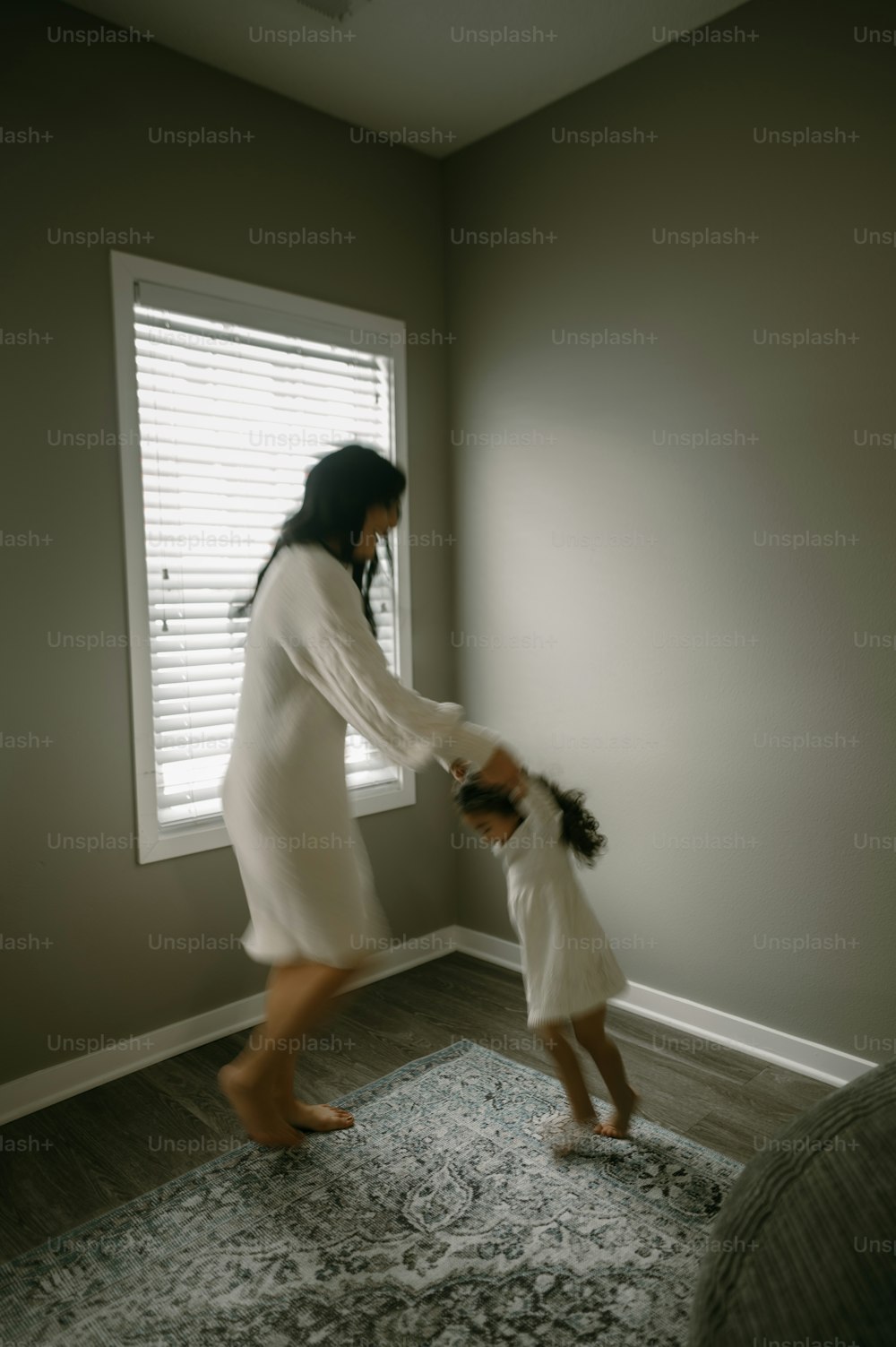 Eine Frau, die die Hand eines kleinen Mädchens hält, während sie vor einem Fenster steht