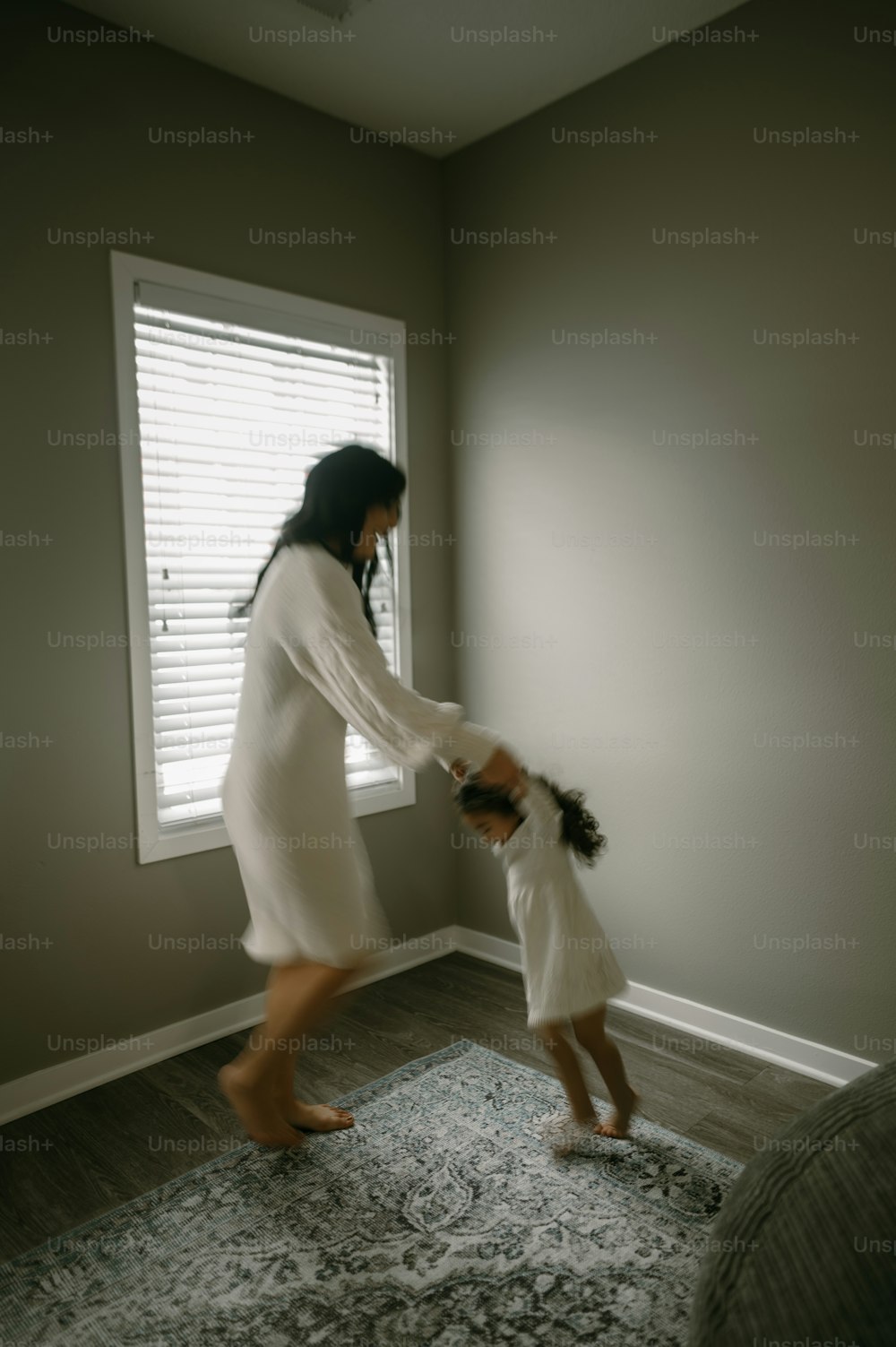 a woman holding a little girl's hand while standing in front of a window