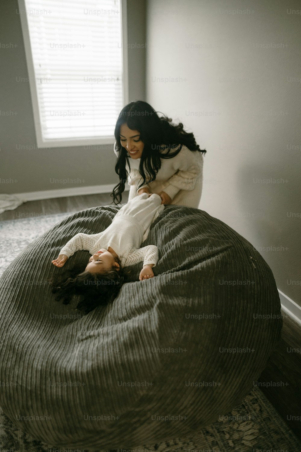 a woman laying on top of a bed next to a little girl