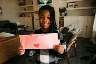 Una niña sosteniendo un pedazo de papel con un corazón dibujado en él
