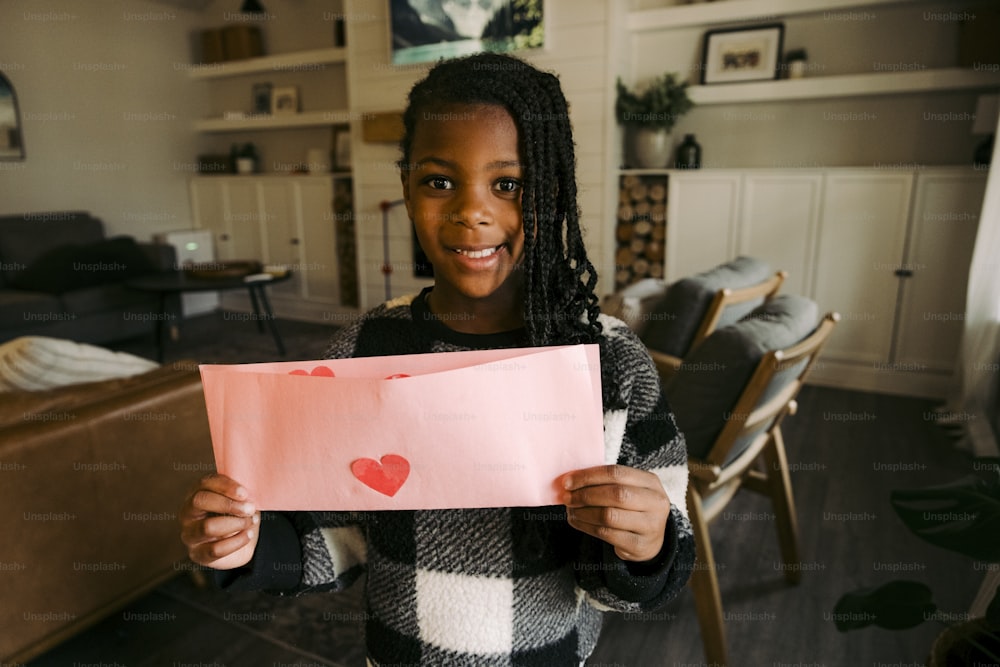 a young girl holding a piece of paper with a heart drawn on it