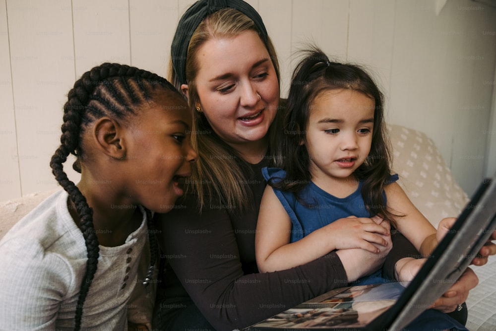 Una mujer y dos niñas mirando una computadora portátil