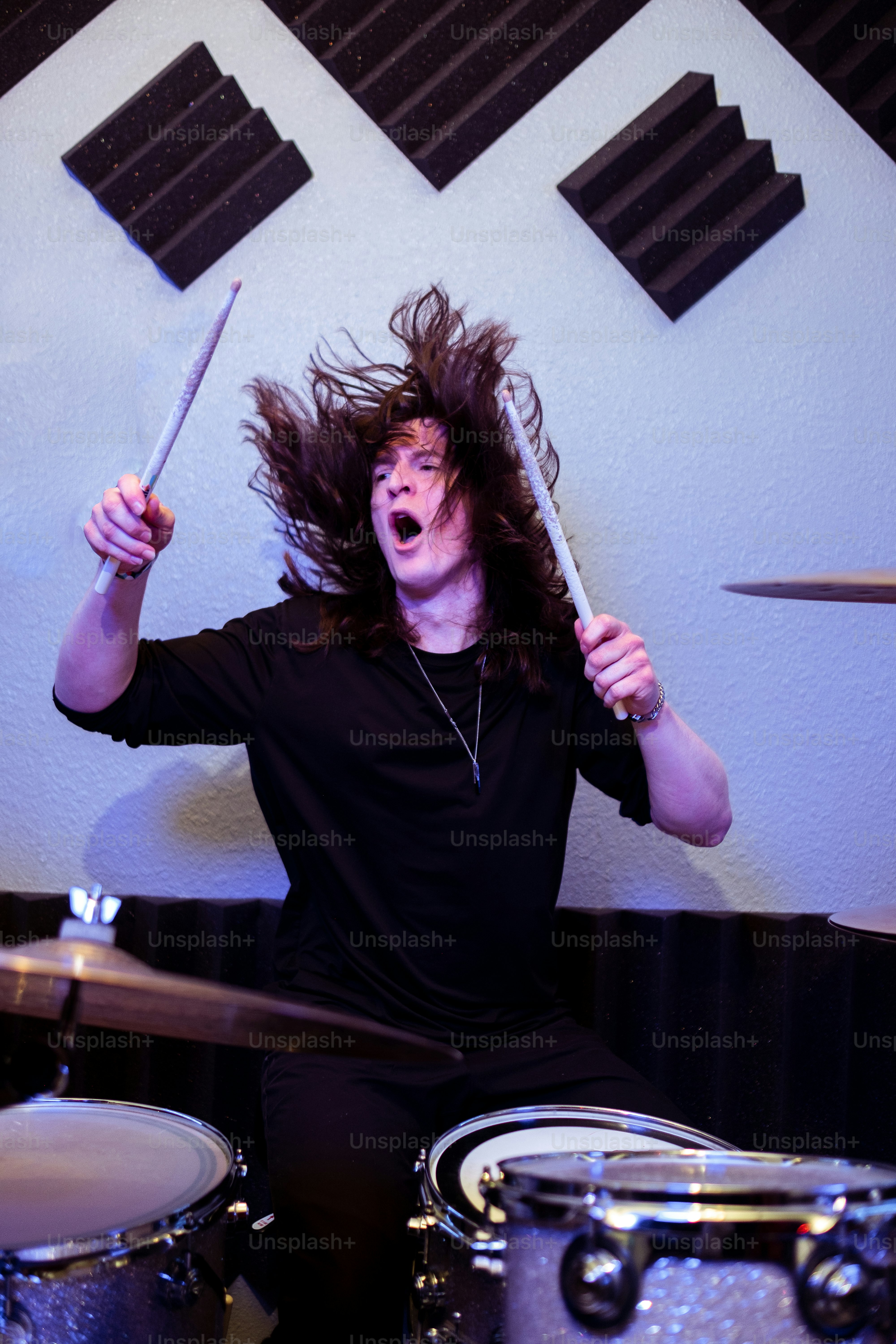 Un uomo con i capelli lunghi seduto davanti a una batteria