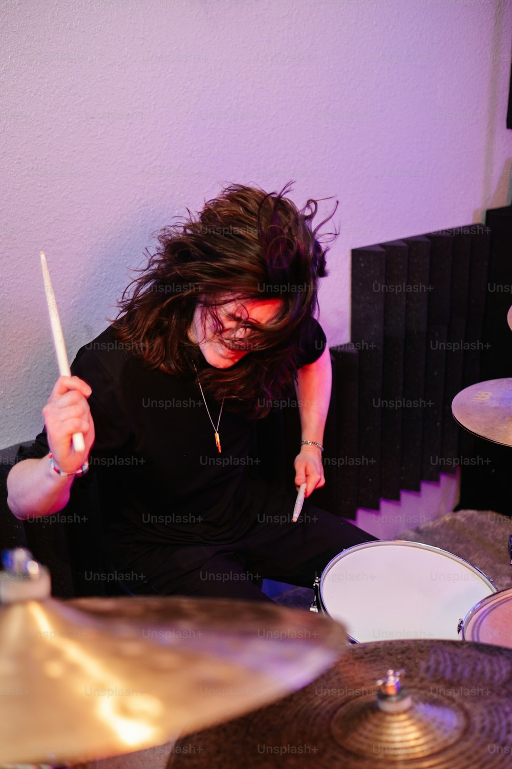 한 여자가 방에서 드럼을 연주하고 있다