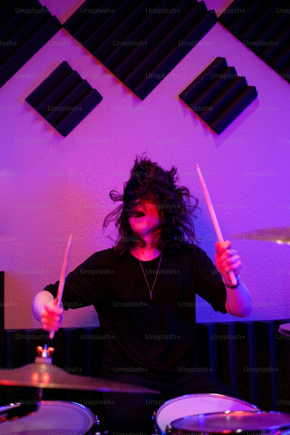 Ein Mann mit langen Haaren spielt Schlagzeug in einem Raum