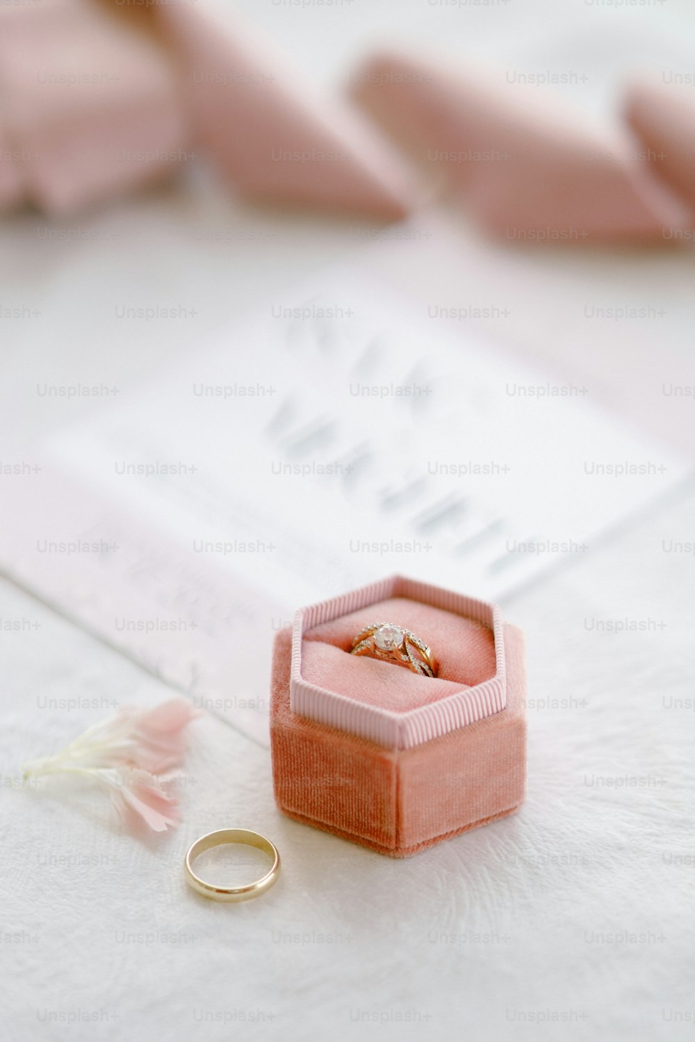una caja de anillos rosa con dos anillos de boda
