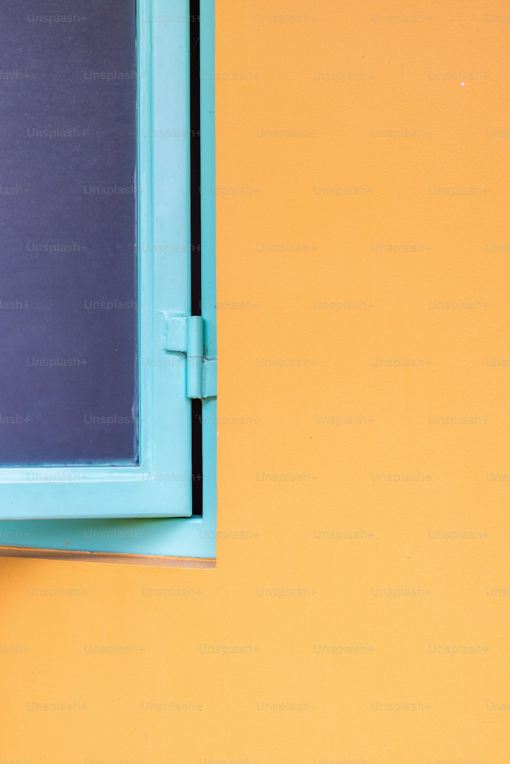 un cadre de fenêtre bleu sur un mur jaune