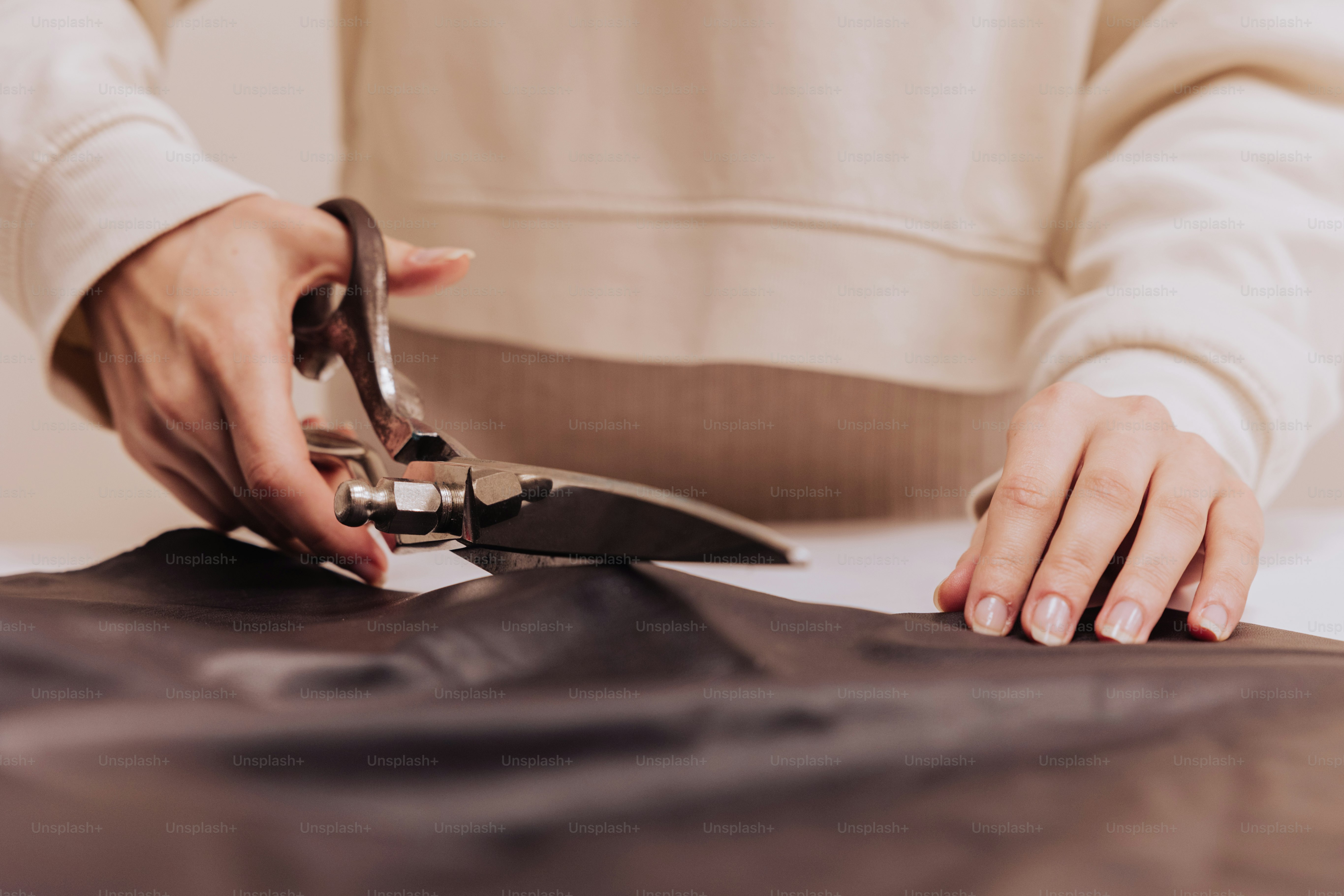a person cutting a piece of leather with a pair of scissors