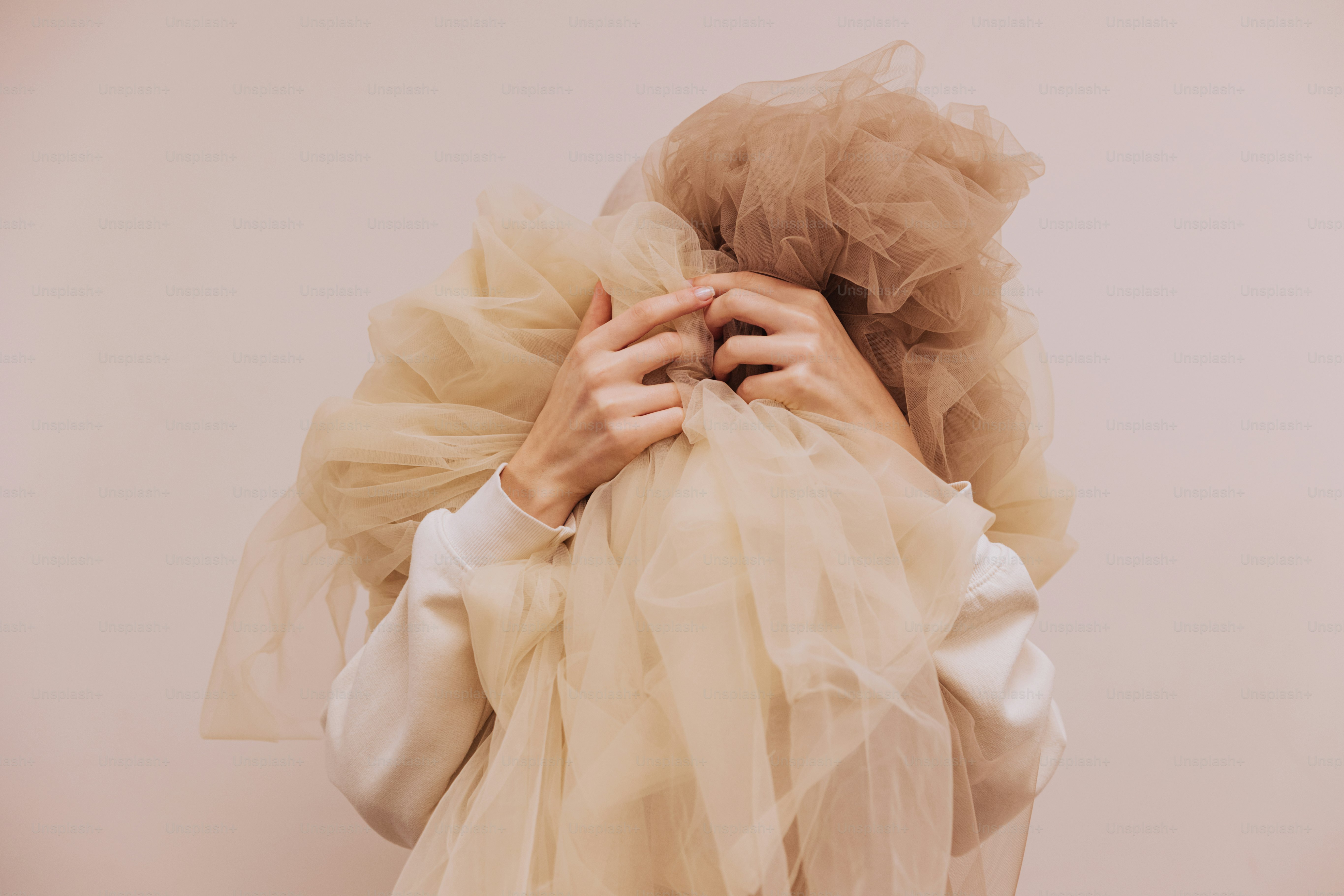 Une femme en chemise blanche se couvre le visage avec un voile
