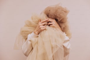 a woman in a white shirt is covering her face with a veil