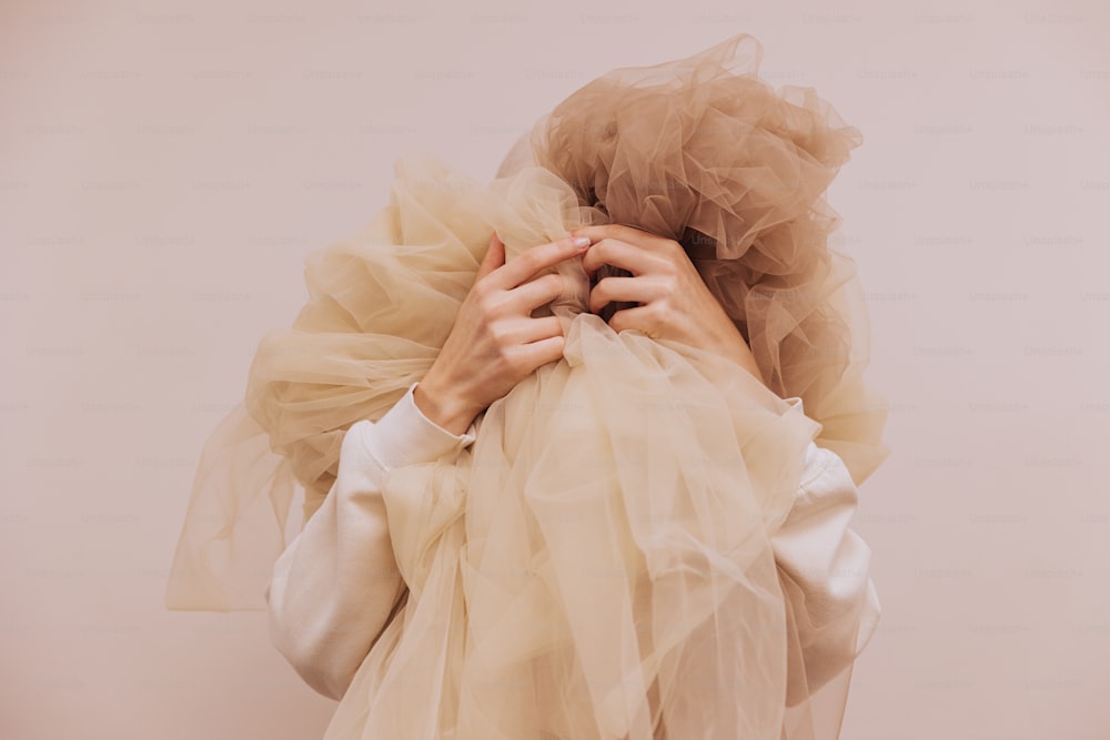Una donna in camicia bianca si copre il viso con un velo