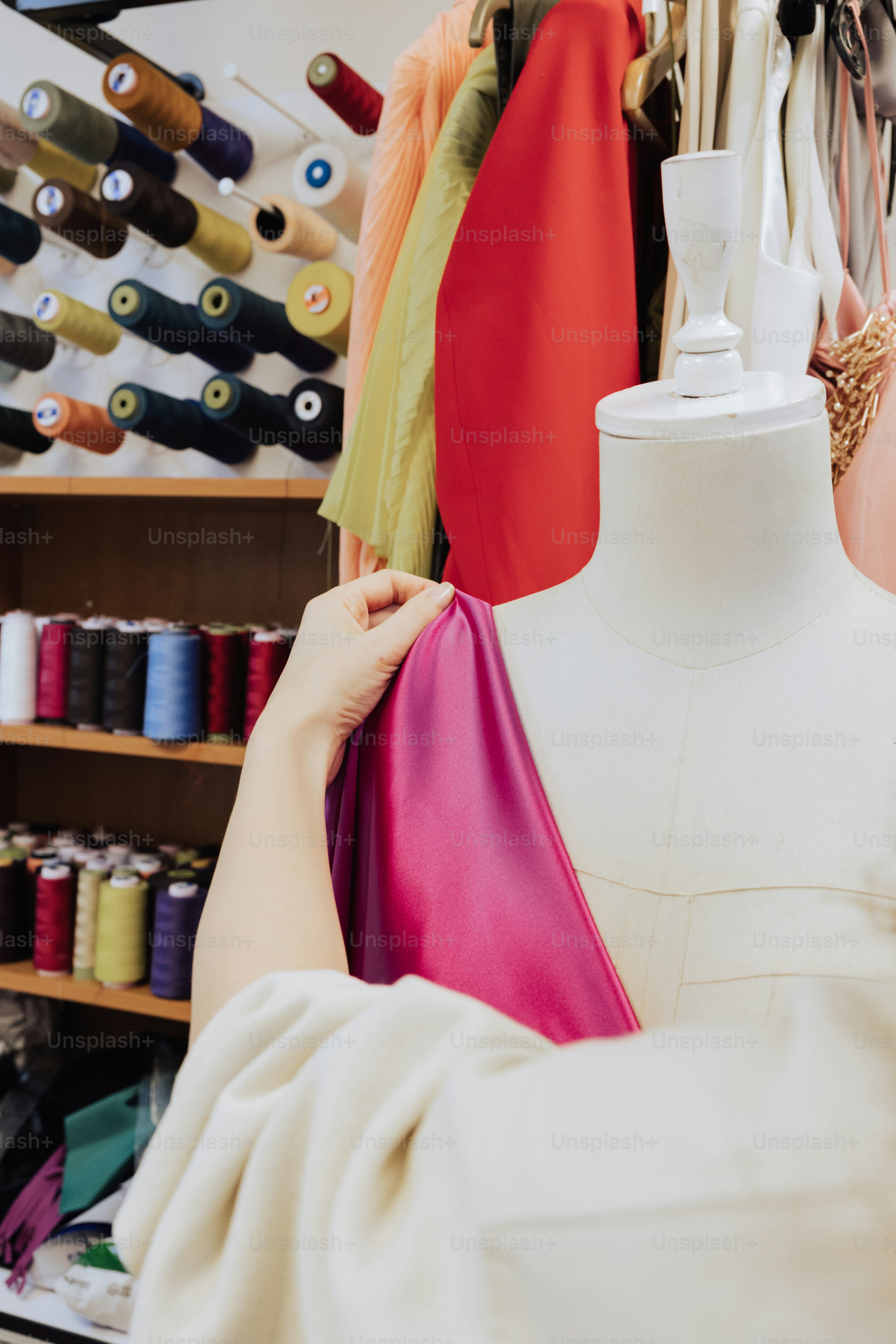 a woman is working on a dress on a mannequin