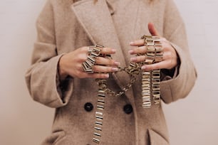 a woman wearing a coat and holding a bunch of bracelets