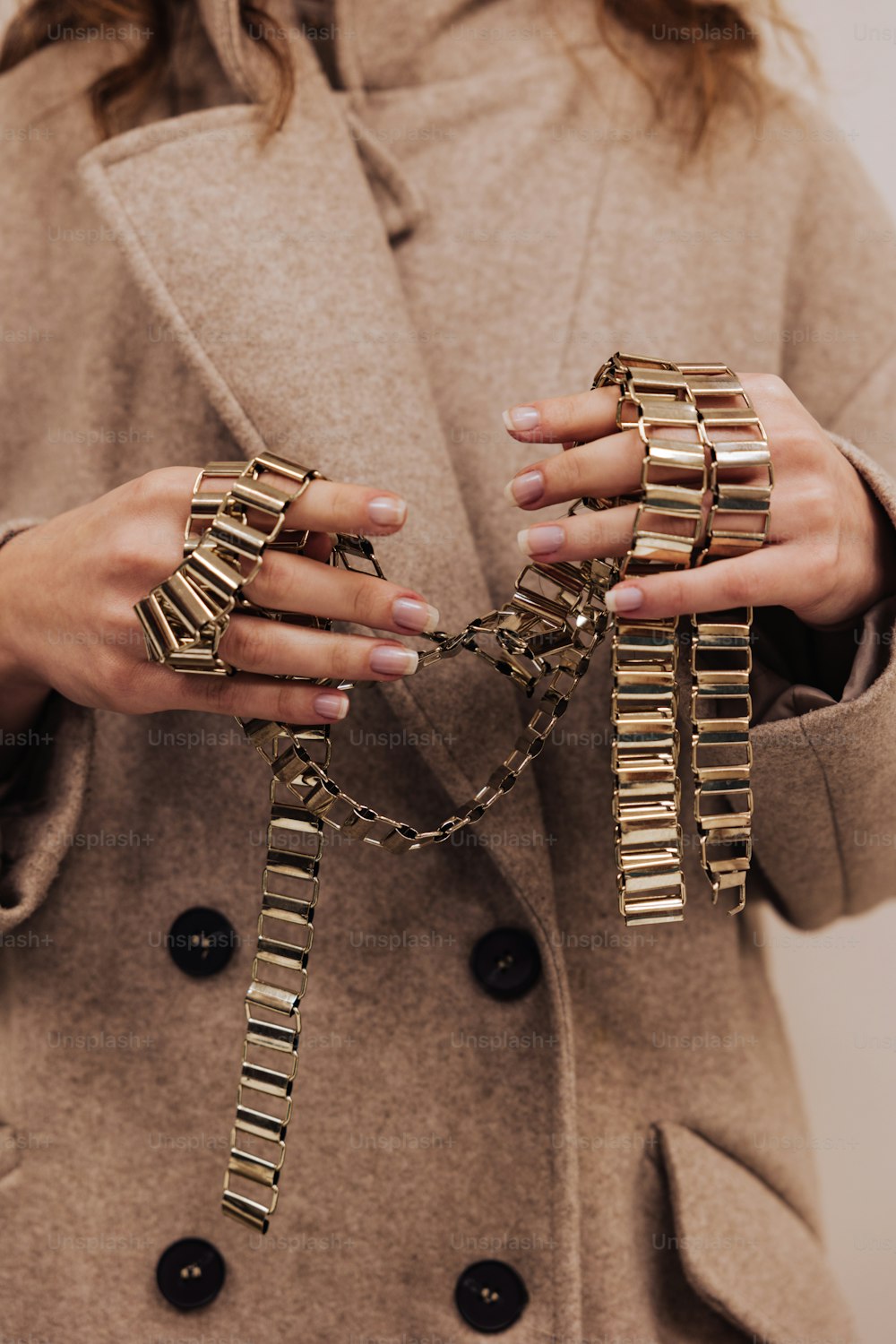 a woman in a coat holding a bunch of gold rings