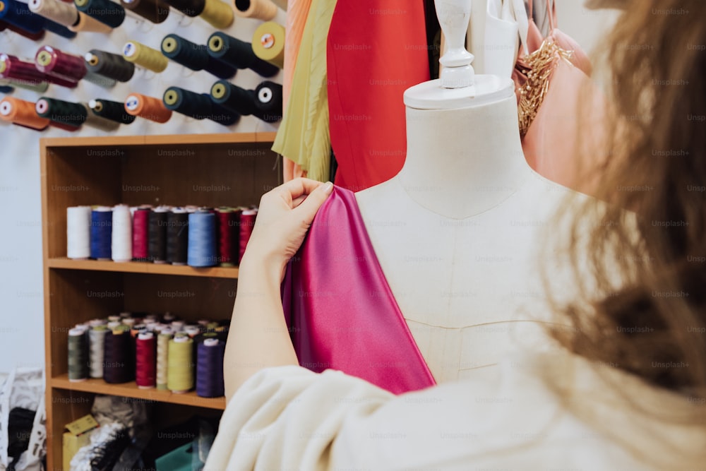 a woman working on a dress on a mannequin