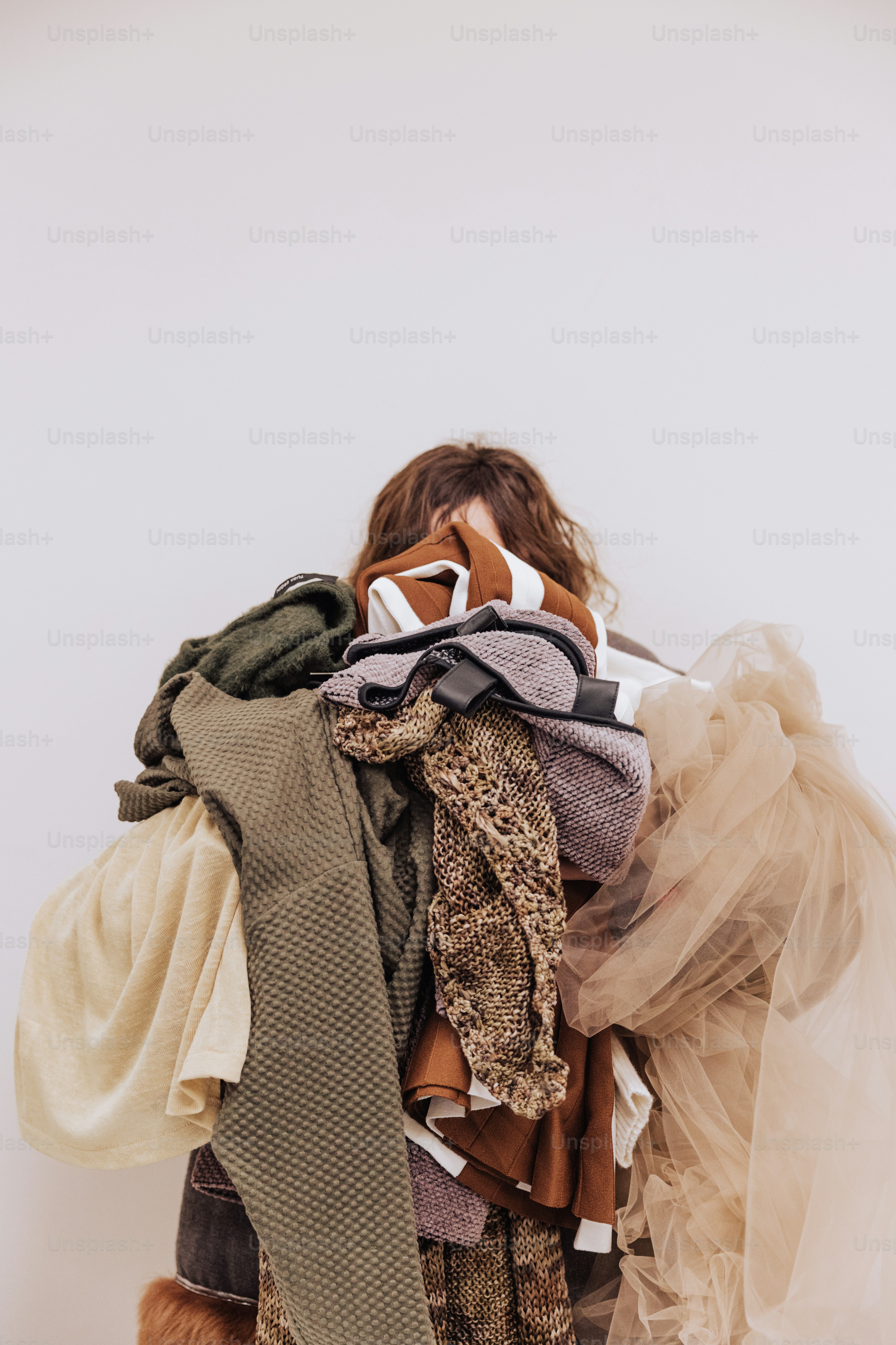 a woman is holding a pile of clothes