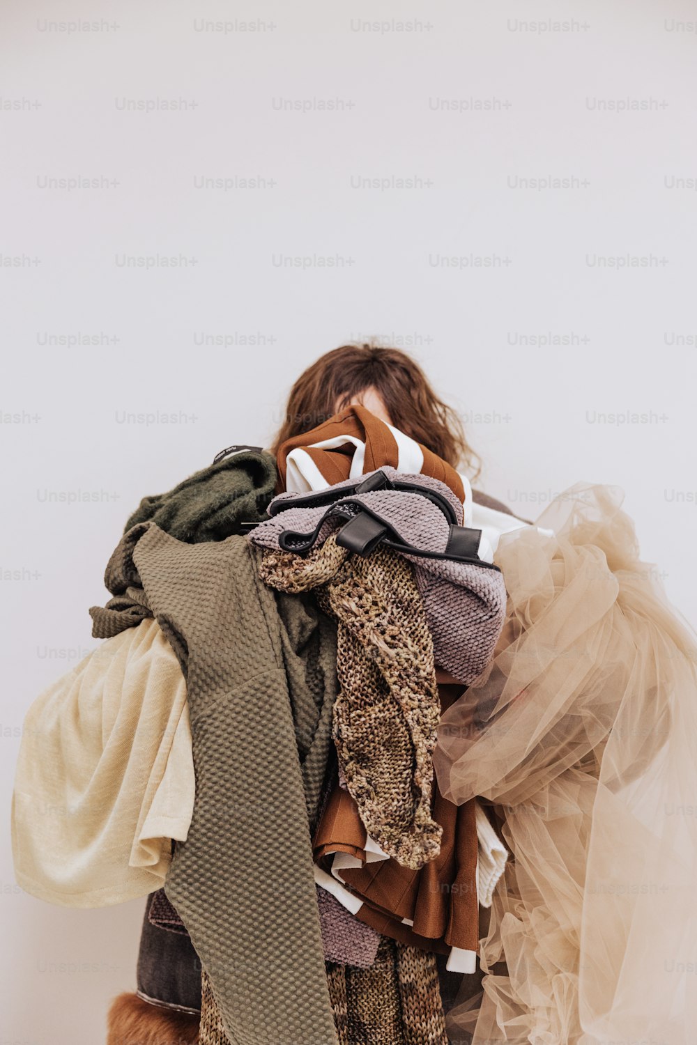 a woman is holding a pile of clothes