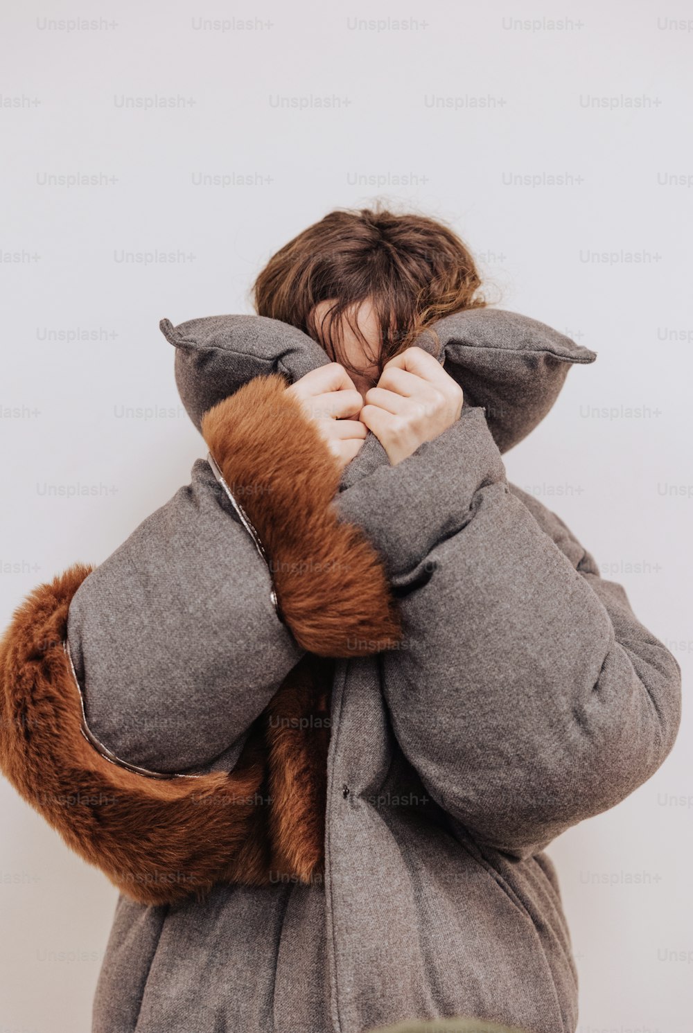a woman is covering her face with her coat