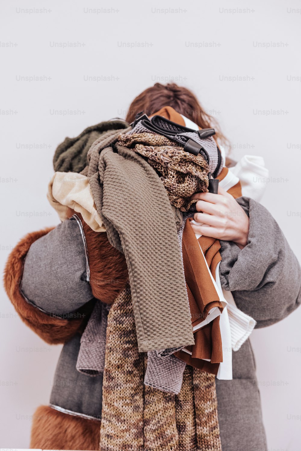 a woman is holding a pile of scarves