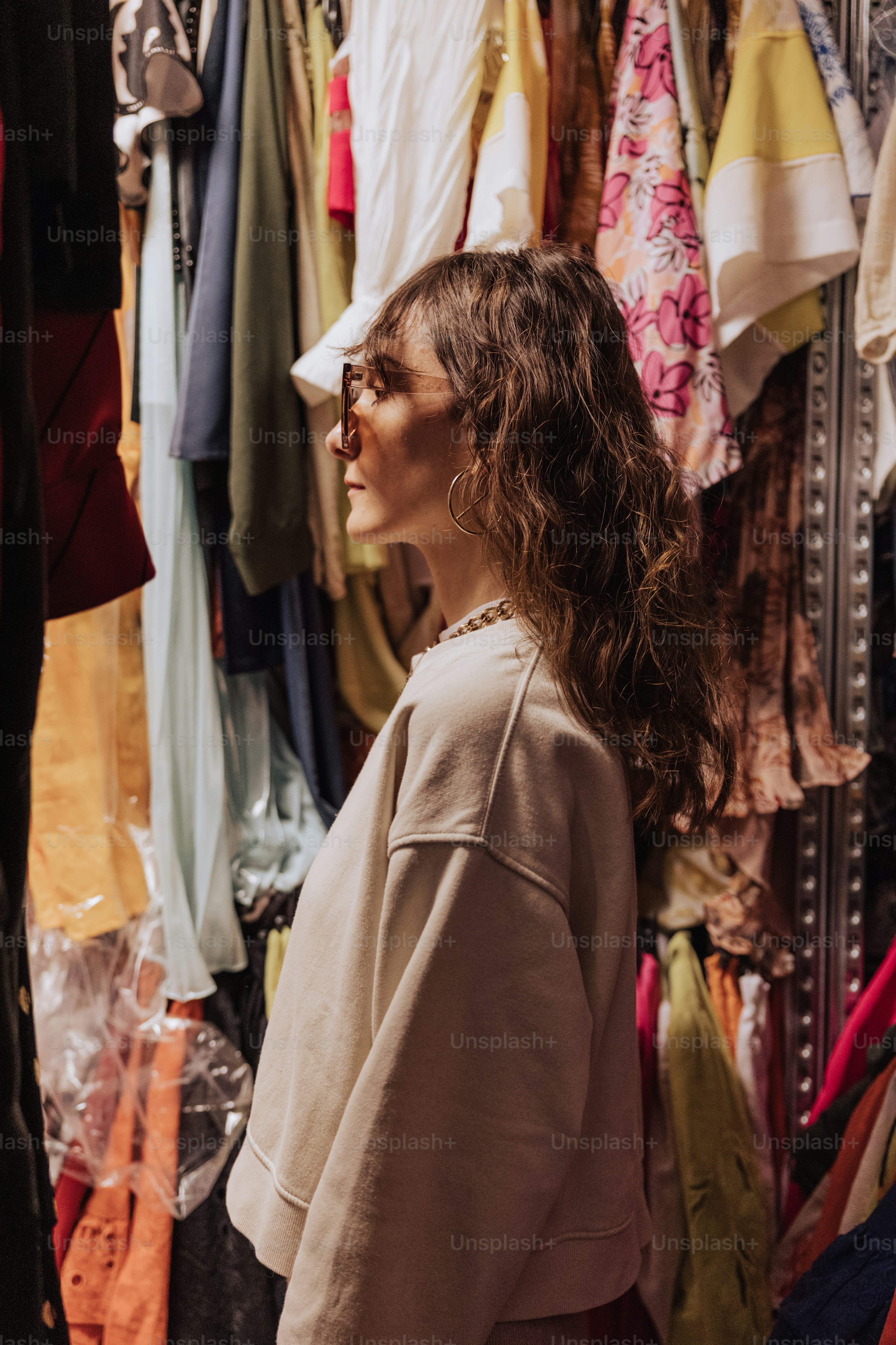 Une femme debout devant un porte-vêtements