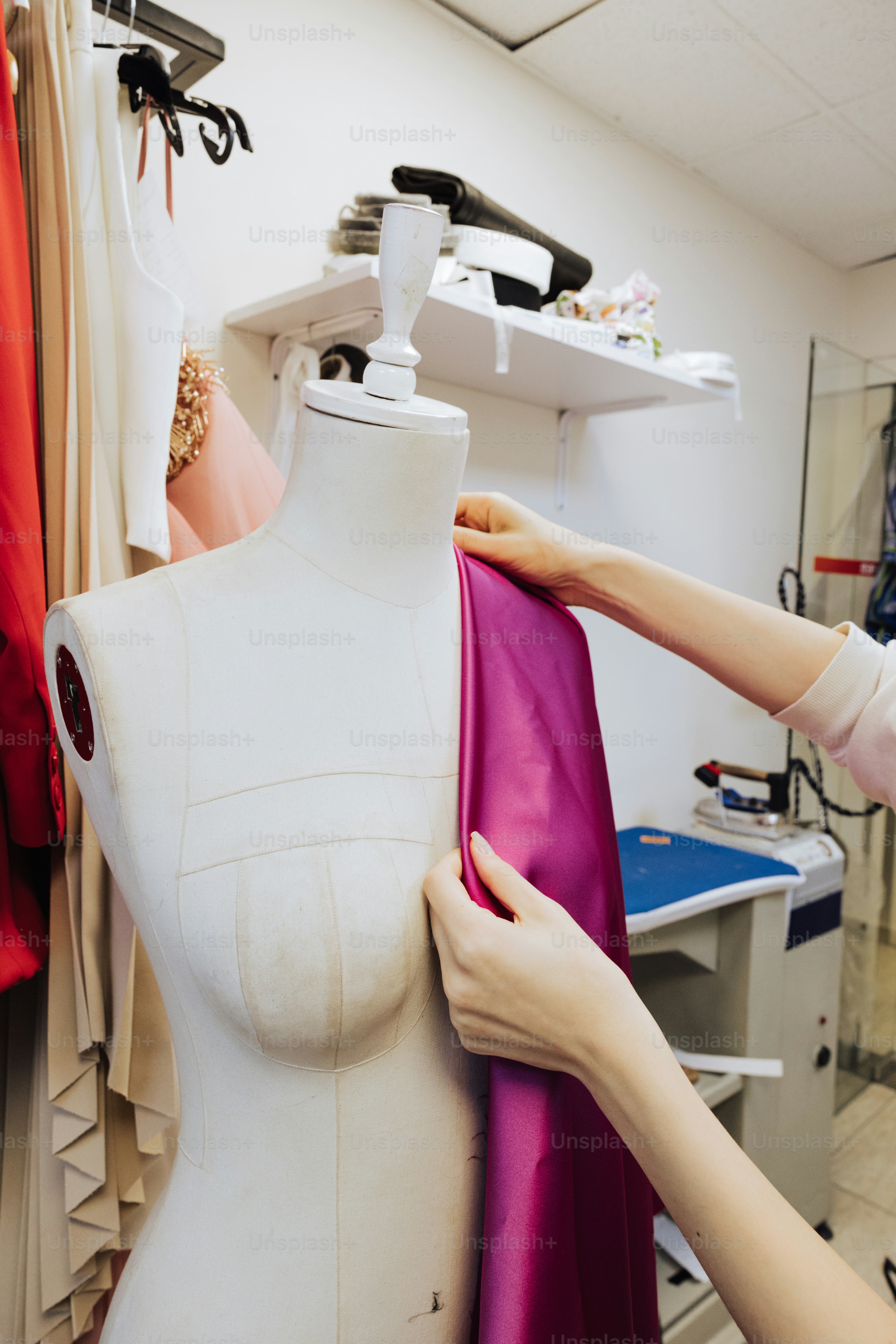 A woman working on a dress on a mannequin photo – Tailors dummy Image ...