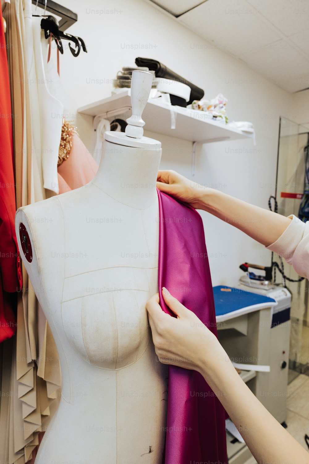 a woman working on a dress on a mannequin