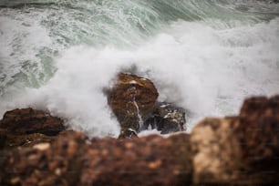 a large wave crashing over some rocks in the ocean