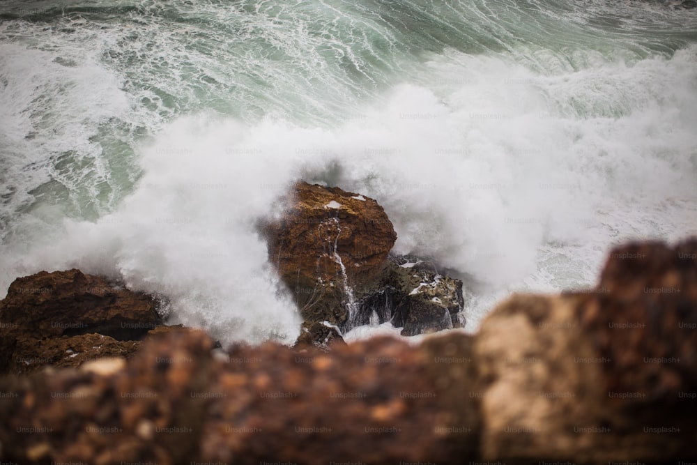 Una grande onda che si infrange su alcune rocce nell'oceano