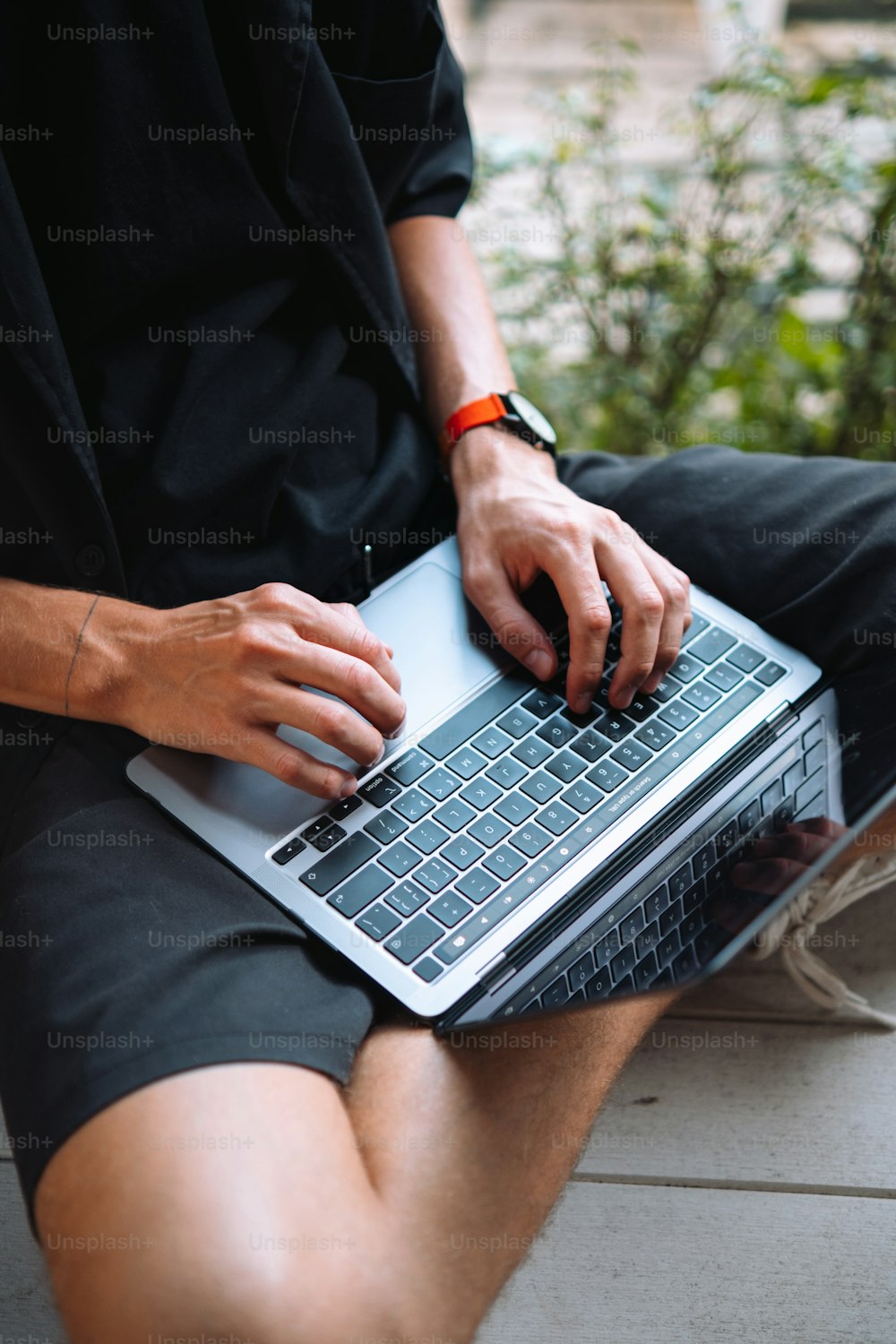 ein Mann, der auf einer Bank sitzt und einen Laptop benutzt