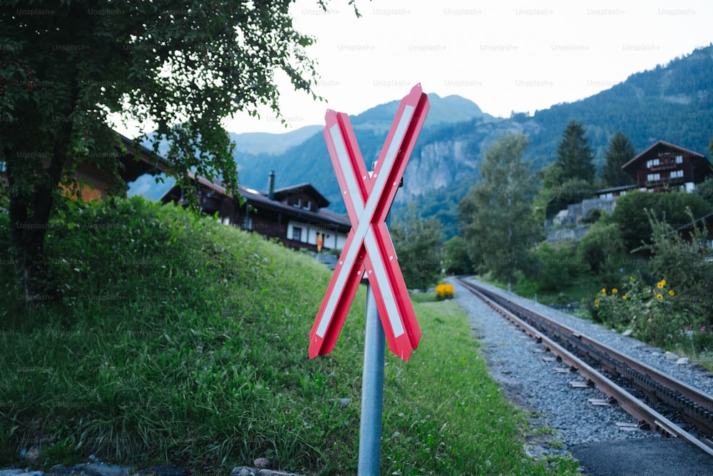 um sinal de travessia ferroviária sentado ao lado de um trilho de trem