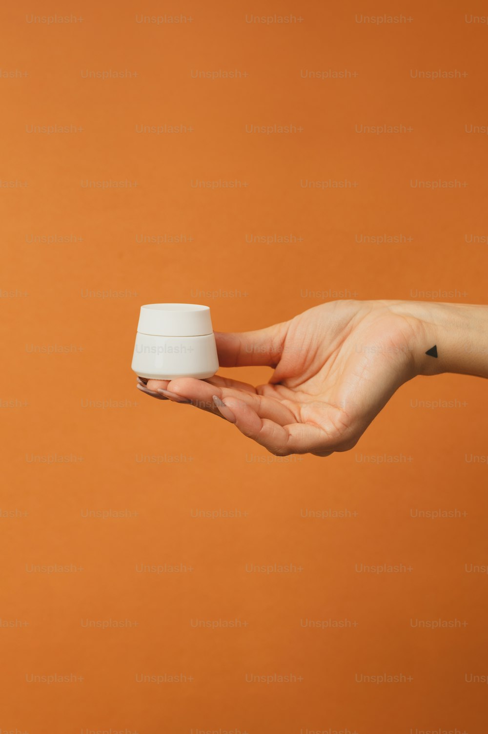 a person's hand holding a small white cup