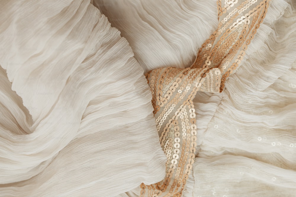 um close up de um vestido branco com lantejoulas douradas
