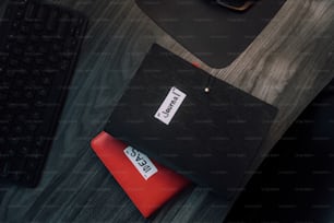 키보드 옆 책상 위에 놓인 검은색과 빨간색 케이스