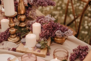 Una mesa cubierta con muchas flores moradas y velas