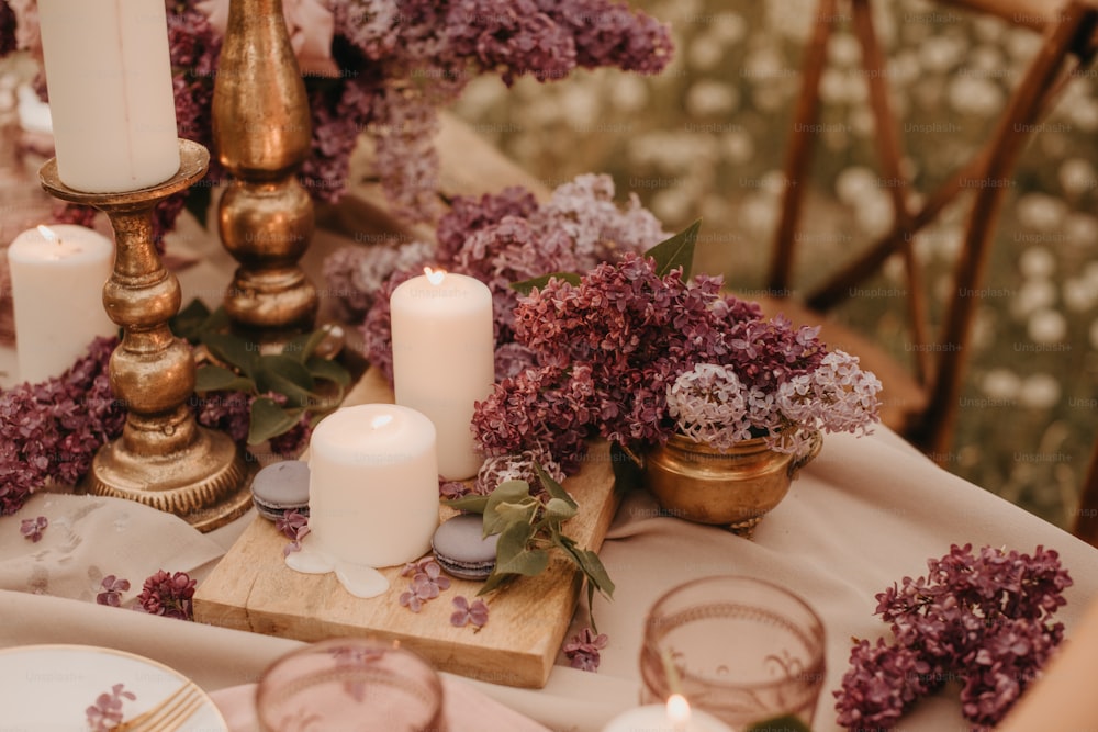 a table topped with lots of purple flowers and candles