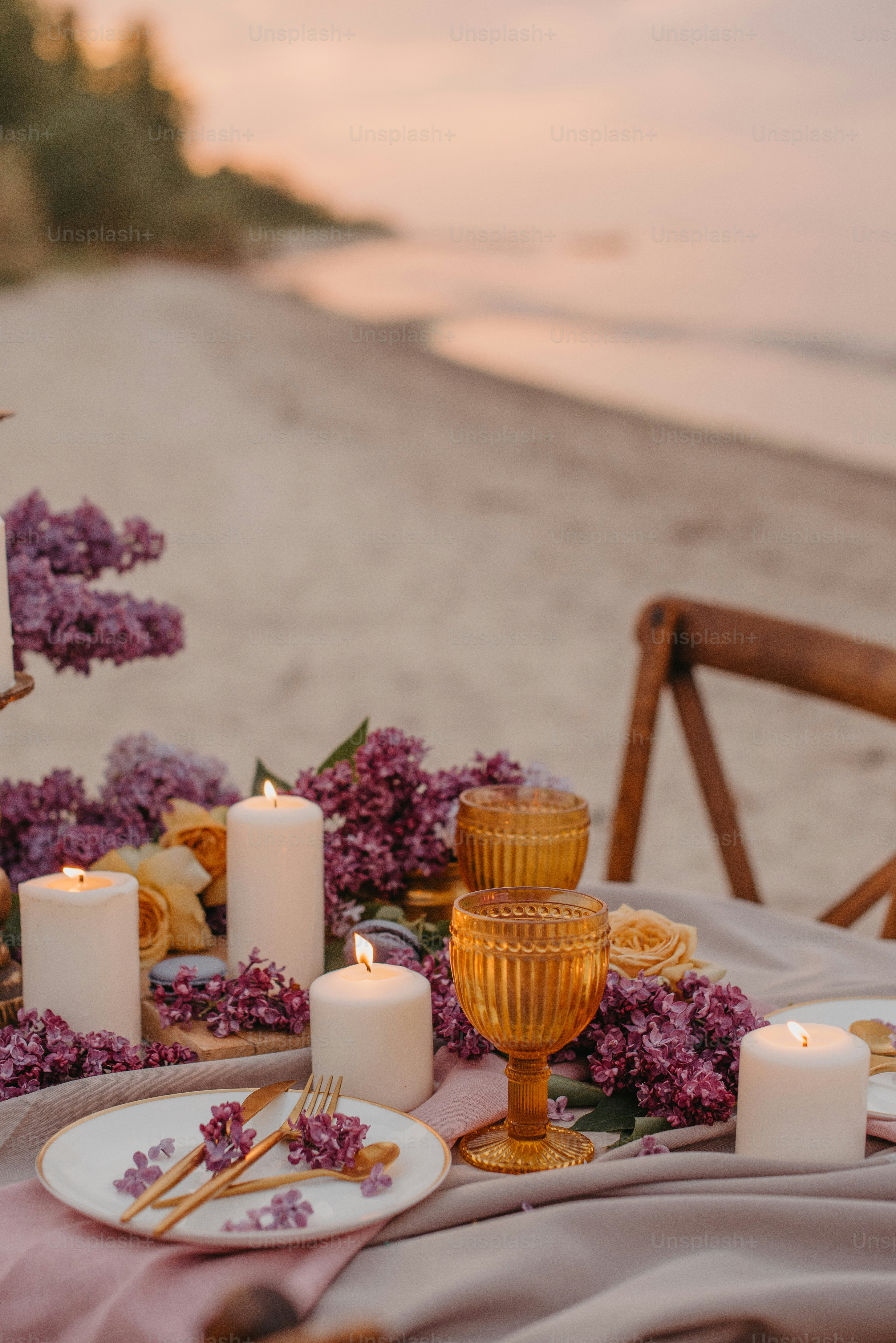 a table set with candles and flowers on the beach