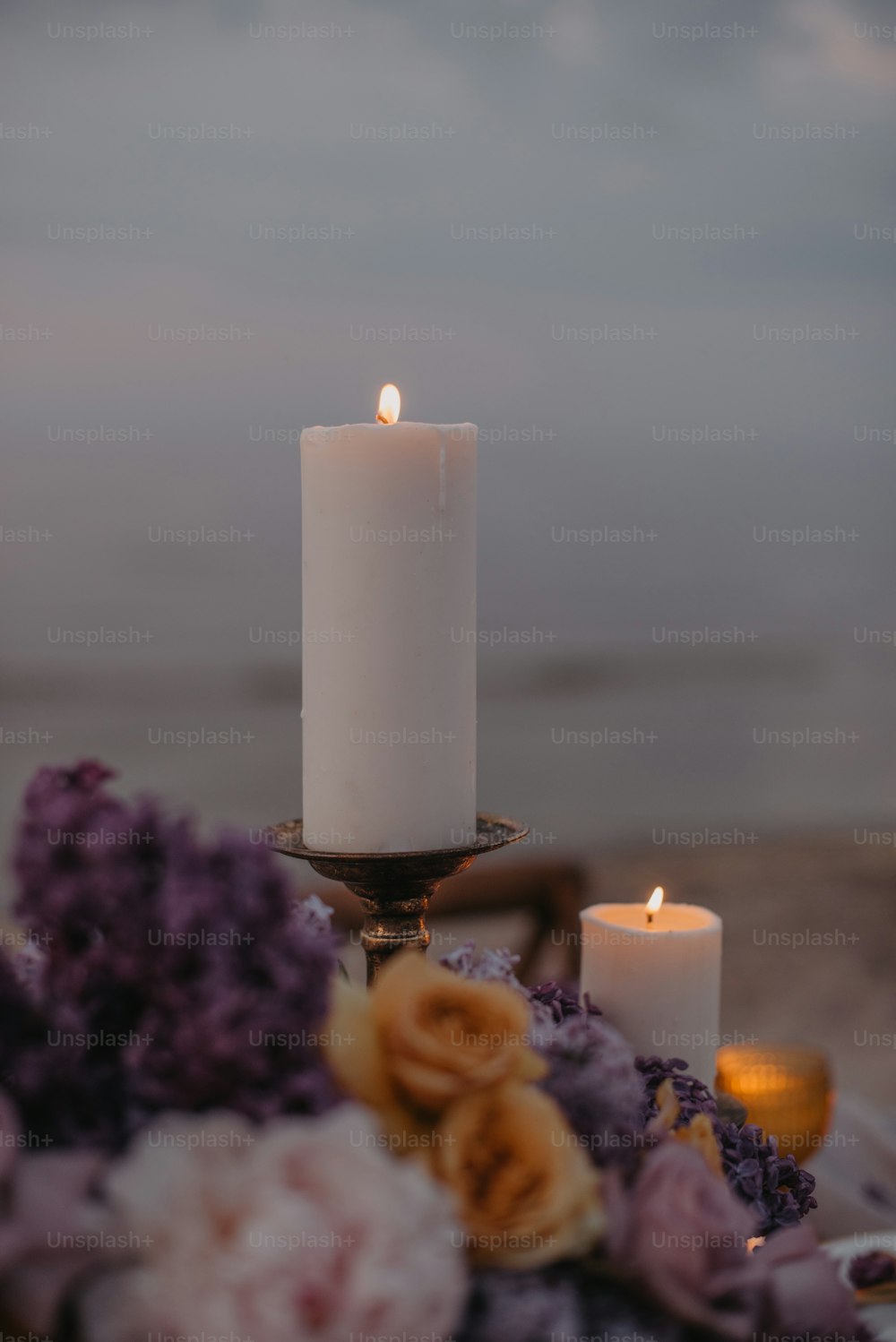 a white candle sitting on top of a table next to flowers