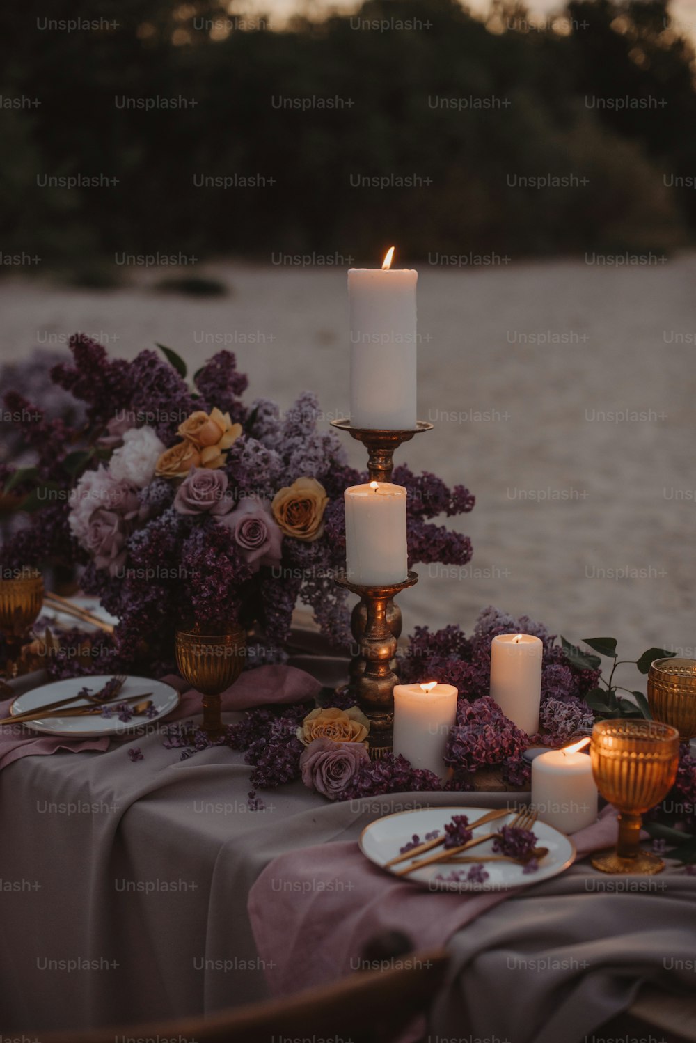 a table topped with lots of purple flowers and candles