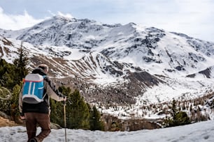 um homem com uma mochila e esquis em uma montanha nevada