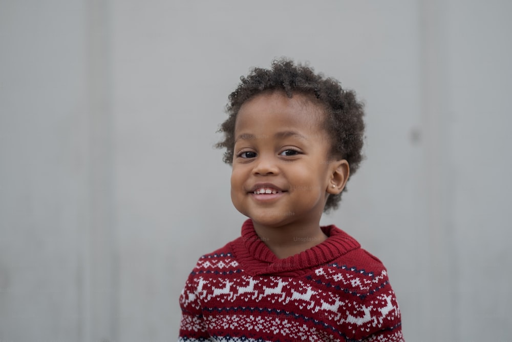 uma criança pequena vestindo um suéter vermelho e branco
