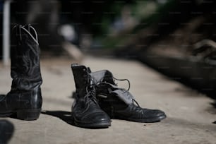 a pair of black boots sitting on top of a sidewalk