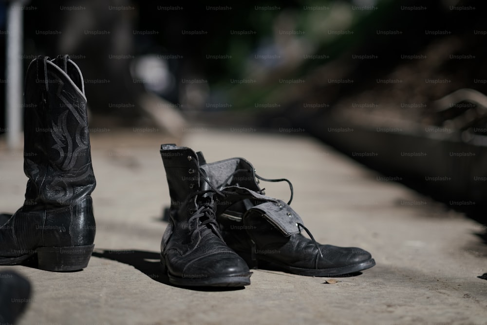 a pair of black boots sitting on top of a sidewalk