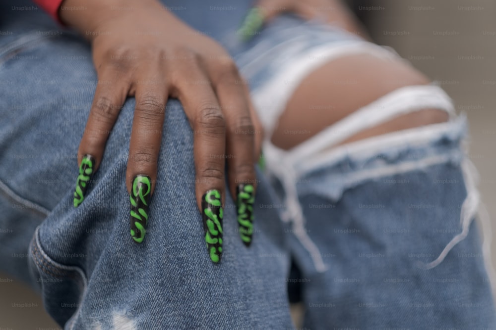 a woman's hand with green nail polish on it